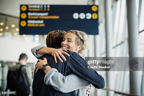 happy businesswoman embracing male colleague at airport - male airport stock-fotos und bilder