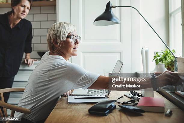 industrial designer adjusting radio while colleague standing in background at home office - kitchen straighten stockfoto's en -beelden