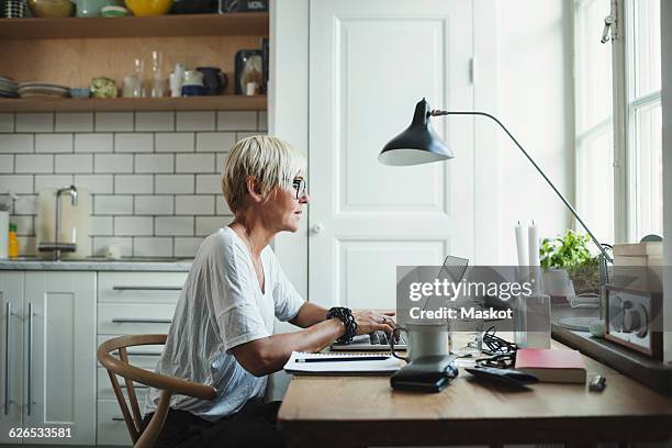 side view of designer using laptop at home office - profile laptop sitting stock-fotos und bilder