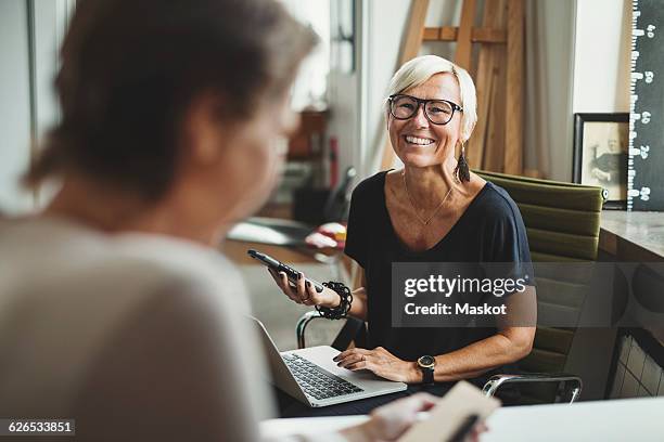 happy industrial designer holding solar product while discussing with colleague at home office - 40 50 business woman stock-fotos und bilder