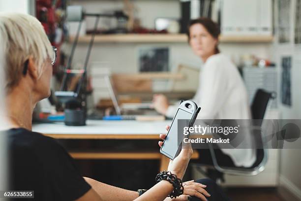 industrial designer holding solar product while discussing with colleague at home office - industrial designer stockfoto's en -beelden