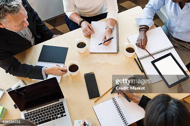 high angle view of business people discussing on table in office - arab businesswoman with books fotografías e imágenes de stock