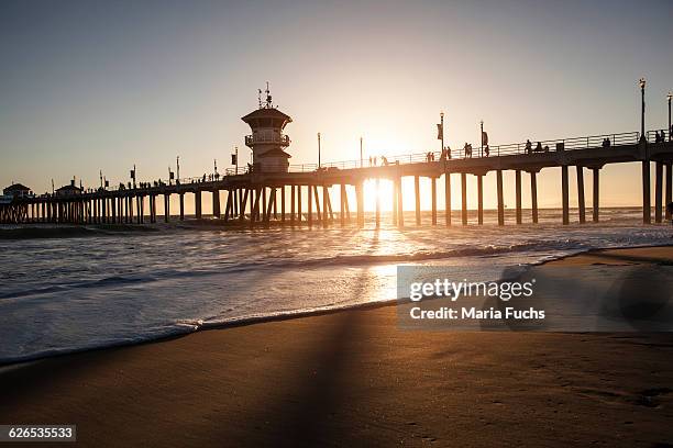 silhouetted view of pier at sunset, huntington beach, california, usa - huntington beach stock-fotos und bilder