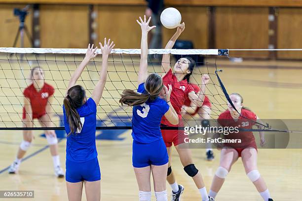 asian high school volleyball player spikes volleyball against female opponents - forward athlete stockfoto's en -beelden