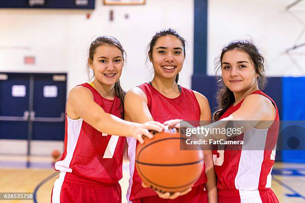 diverse group of female basketball players holding a basketball - teenage girl basketball stock pictures, royalty-free photos & images