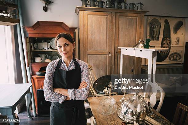 portrait of confident female owner standing in antique shop - antique furniture stock-fotos und bilder