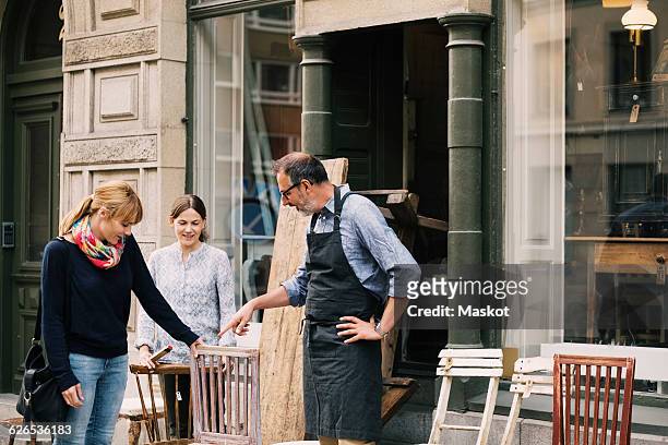 smiling retailers assisting woman outside shop - 骨董品　店 ストックフォトと画像