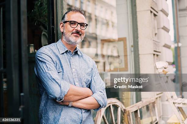 portrait of owner standing with arms crossed outside antique shop - antique shop stock-fotos und bilder