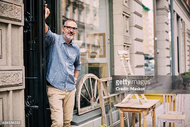 portrait of owner standing with hand on hip at antique shop - retail occupation stockfoto's en -beelden