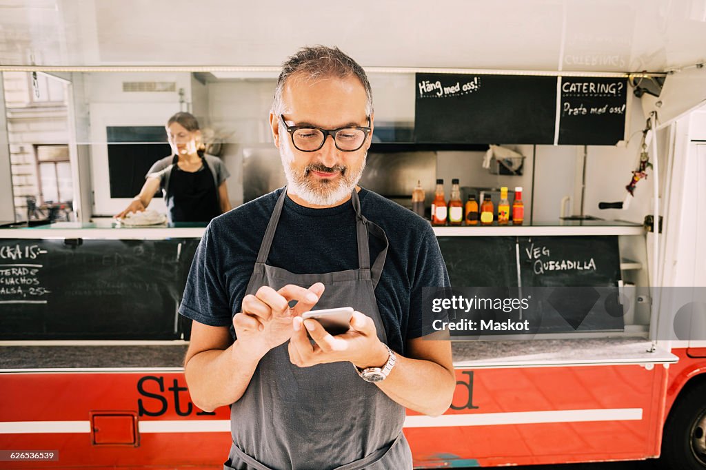 Owner using mobile phone against street food truck