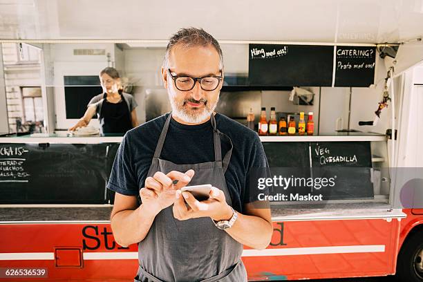 owner using mobile phone against street food truck - chef apron stock pictures, royalty-free photos & images