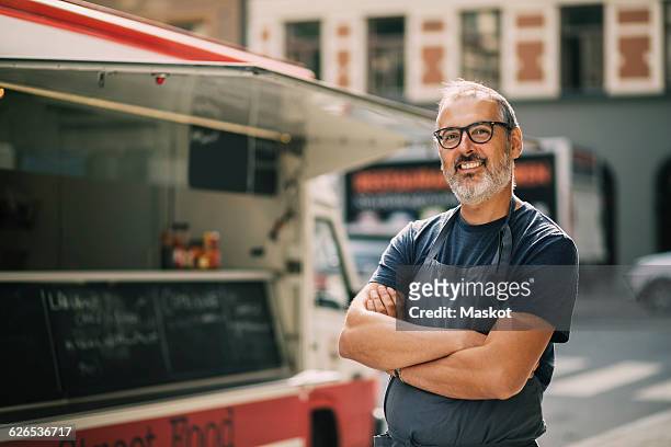 portrait of confident chef with arms crossed standing by food truck on street - happy merchant fotografías e imágenes de stock