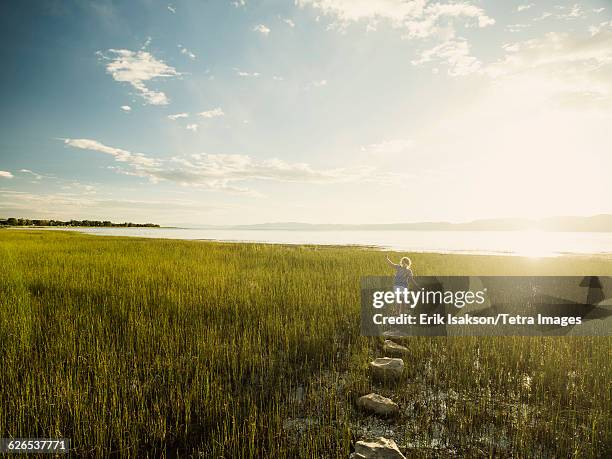 usa, utah, garden city, small girl (4-5) walking on stepping stones in meadow - stepping stones stockfoto's en -beelden