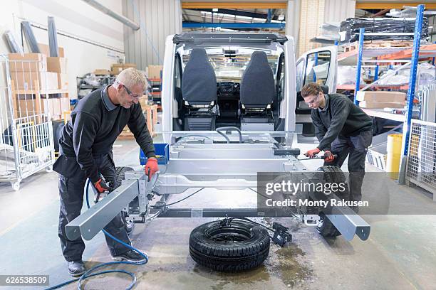 workers fitting chassis on motorhome production line - fahrgestell stock-fotos und bilder