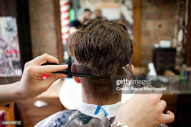 rear view of young man in barbershop having haircut - barbero peluquería fotografías e imágenes de stock