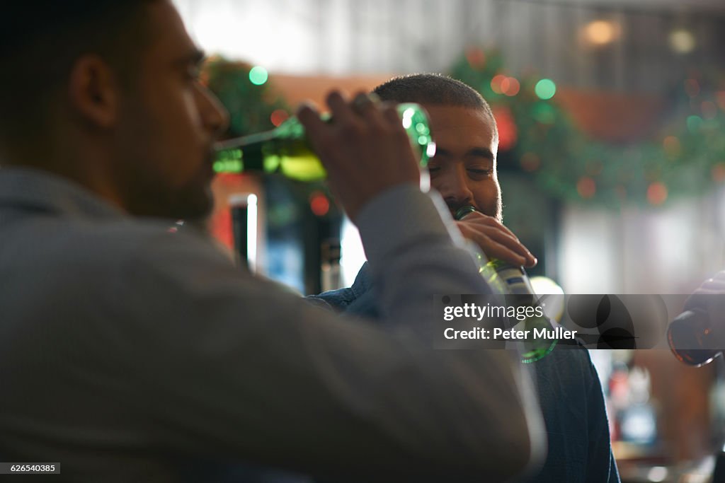 Young men in public house drinking beer from bottles