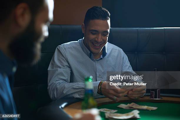 male friends playing card game for cash at pub card table - card table stock pictures, royalty-free photos & images
