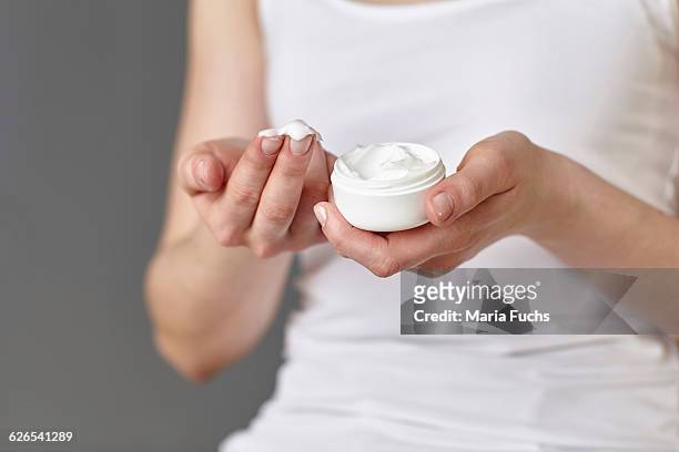 cropped shot of young woman with moisturiser on fingertips - dry skin - fotografias e filmes do acervo