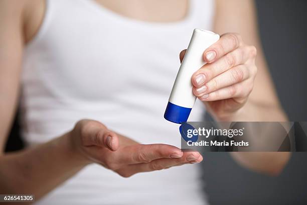 cropped shot of young woman holding tube of moisturiser - creme tube stock pictures, royalty-free photos & images