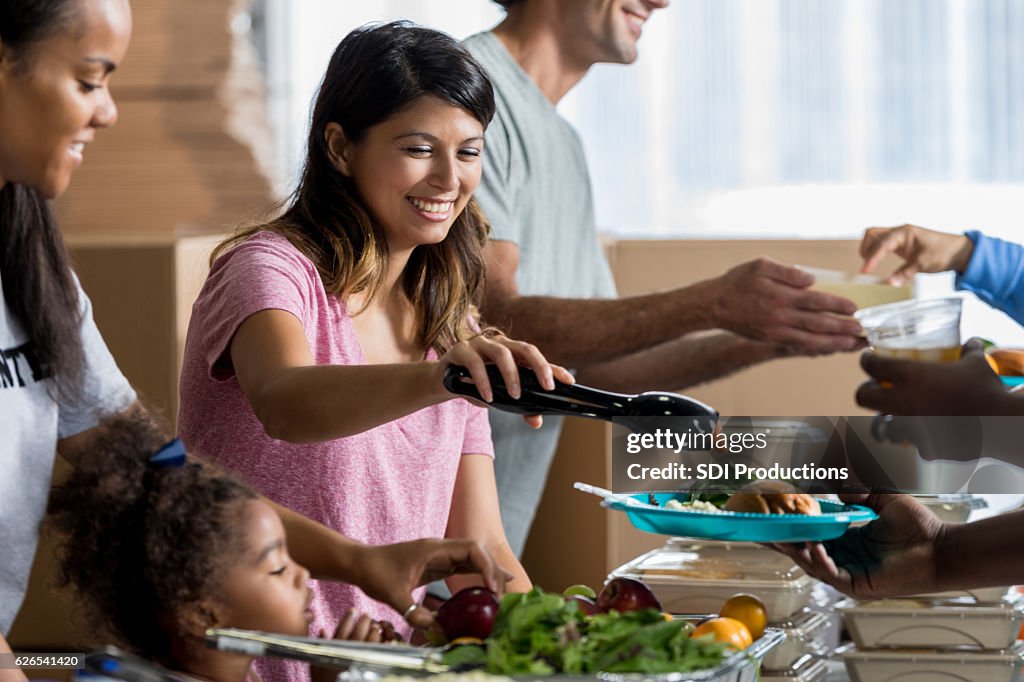 Beautiful Hispanic woman serves a meal in soup kitchen