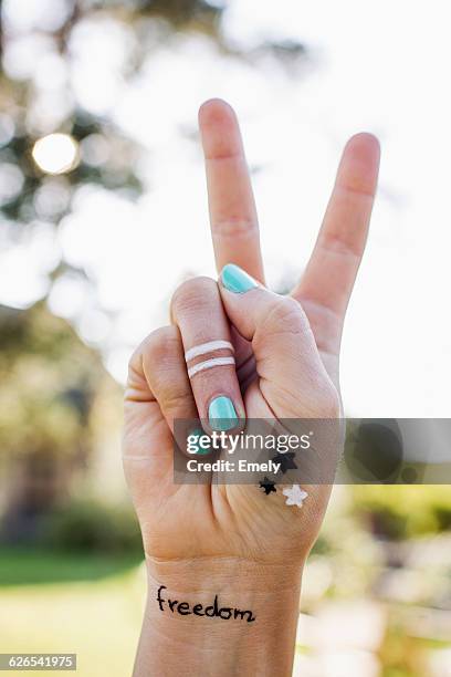 woman making peace sign with hand - hippie photos et images de collection