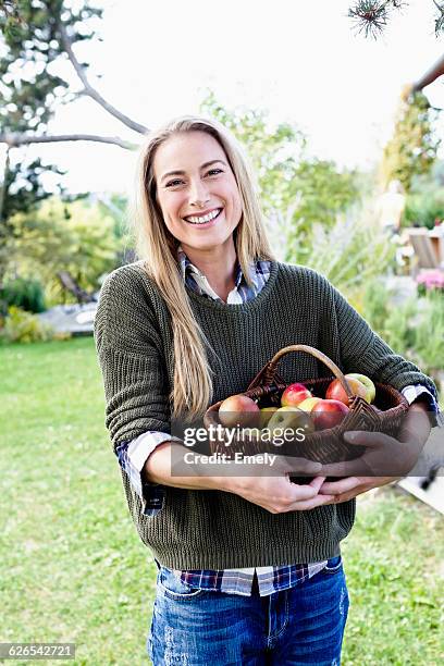 mid adult woman holding basket of apples, portrait - harvest basket stock pictures, royalty-free photos & images