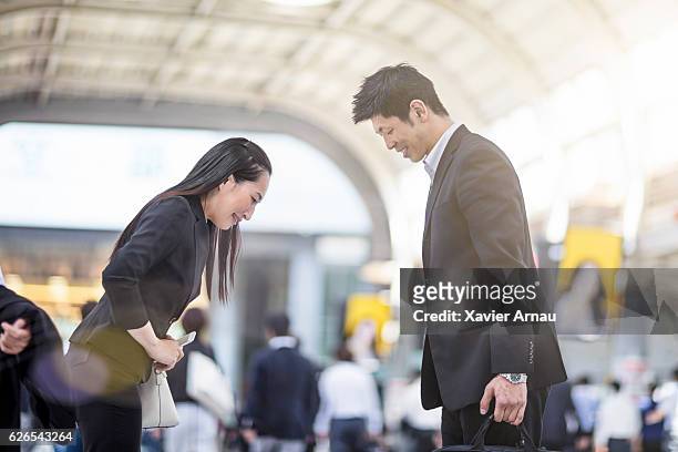 japanese business people bowing to each other at station - bowing stock pictures, royalty-free photos & images