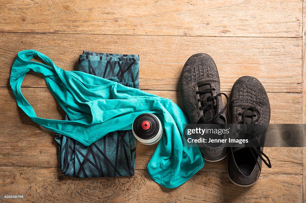Flat Lay image of sports clothes and shoes on a wooden floor.