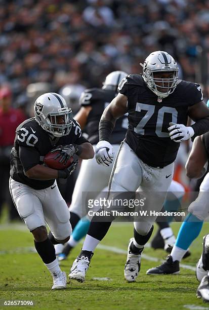 SaQwan Edwards of the Oakland Raiders carries the ball lead by tackle Kelechi Osemele against the Carolina Panthers during an NFL football game on...