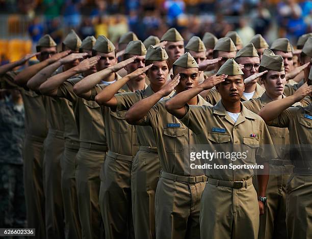 Military personnel salute during the National Anthem during a NCAA football game between the Pittsburgh Panthers and the Villanova Wildcats at Heinz...