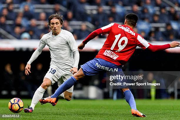 Luka Modric of Real Madrid fights for the ball with Carlos Carmona Bonet of Real Sporting de Gijon during the La Liga match between Real Madrid and...