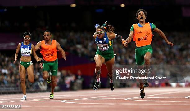 Terezinha Guilhermina of Brazil and guide Guilherme Soares de Santana cross the line to win gold ahead of silver medallists Jerusa Gerber Santos of...