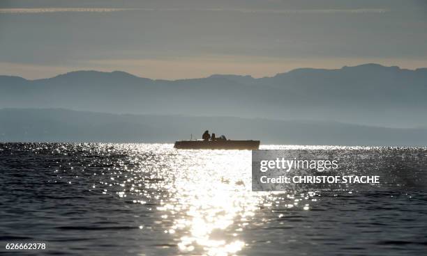 People sit in a boat on the Starnberger See lake as in background can be seen an Alps panorama in Tutzing, southern Germany, where temperatures...