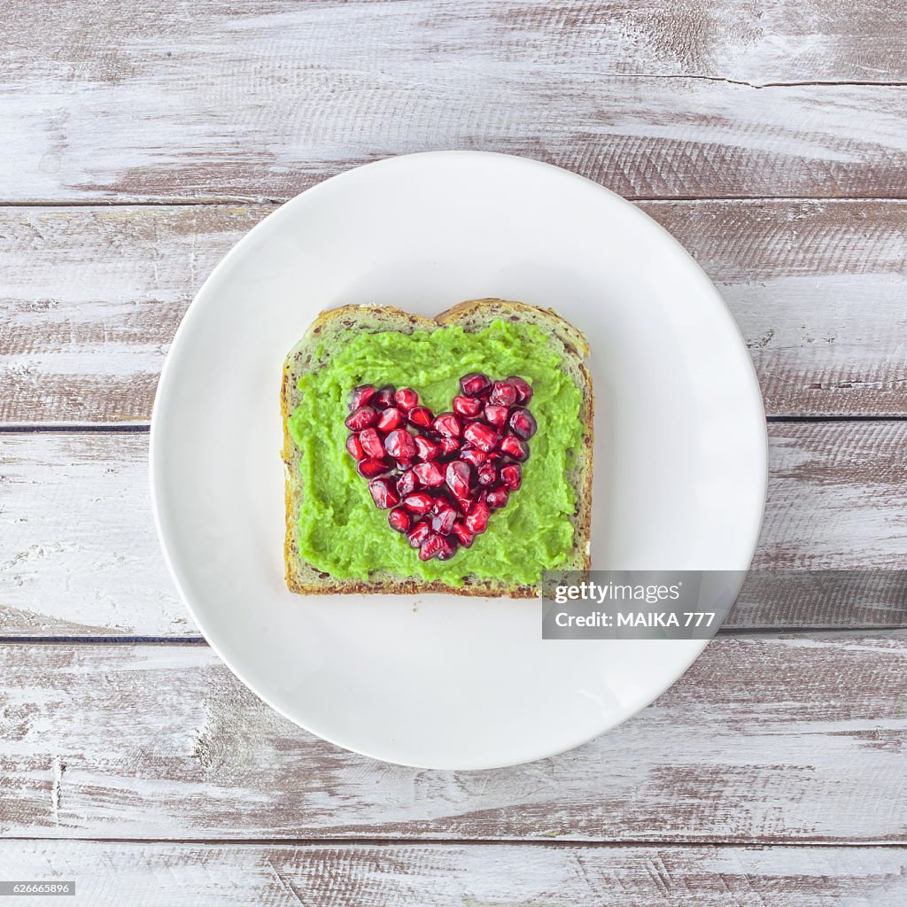 Pomegranate seeds and smashed avocado on seeds toast.