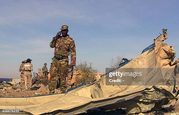 Soldiers talks on the phone next to debris following a suicide car bomb attack revendicated by the Algerian jihadist group Mokhtar Belmokhtar at the...