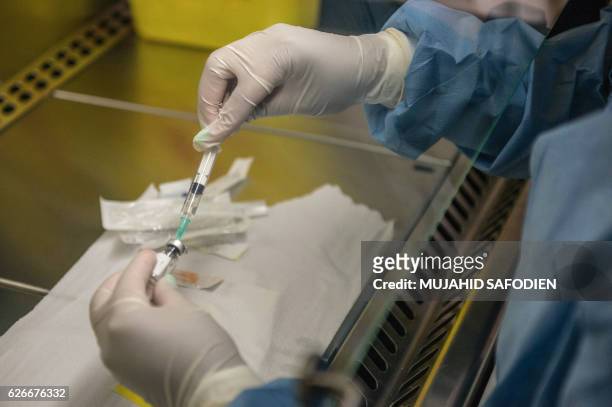 Person holds an experimental vaccine against the AIDS virus in Shoshaguve, near Pretoria, on November 30, 2016 as South Africa launched a major...