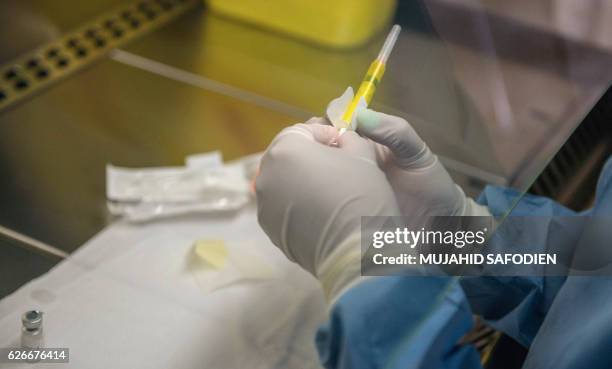 Person holds an experimental vaccine against the AIDS virus in Shoshaguve, near Pretoria, on November 30, 2016 as South Africa launched a major...