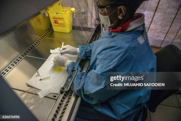 Person holds an experimental vaccine against the AIDS virus in Shoshaguve, near Pretoria, on November 30, 2016 as South Africa launched a major...