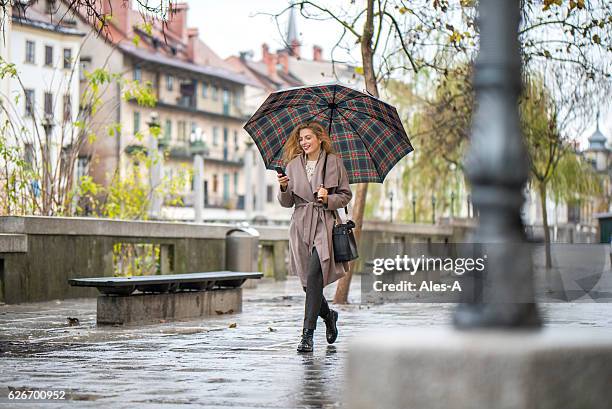 woman with umbrella walking down the street - fashion avenue stock pictures, royalty-free photos & images