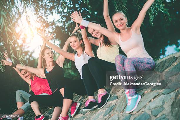 gruppe von frauen mit erhobenen händen nach übung in der natur - girls in leggings stock-fotos und bilder