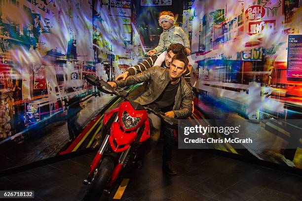 Man poses for a photograph with his daughter on a waxwork figure of Tom Cruise on display at Turkey's first Madame Tussauds Wax Museum on November...