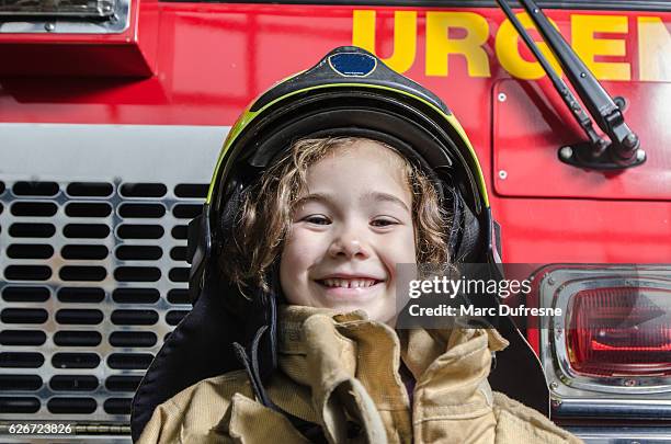 young girl wearing fireman coat and helmet - firefighters helmet stock pictures, royalty-free photos & images