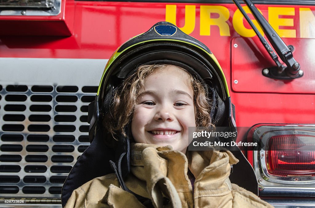 Jovem usando casaco de bombeiro e capacete