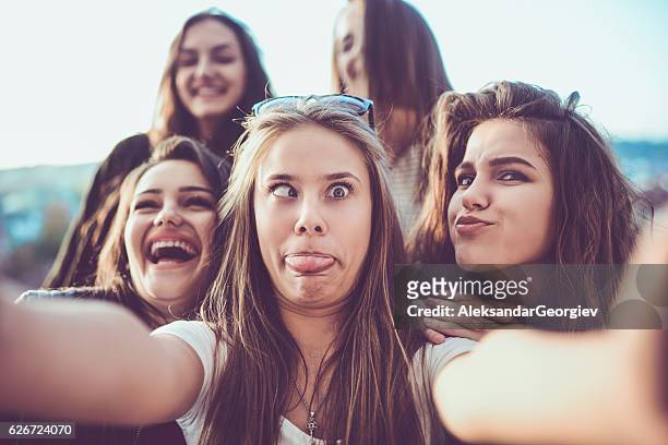 grupo de chicas locas tomando selfie y haciendo caras al aire libre - poner caras fotografías e imágenes de stock