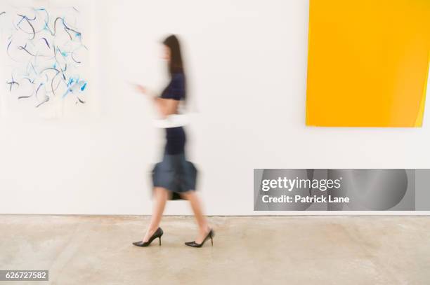 woman walking through an art gallery - patrick walker stock pictures, royalty-free photos & images