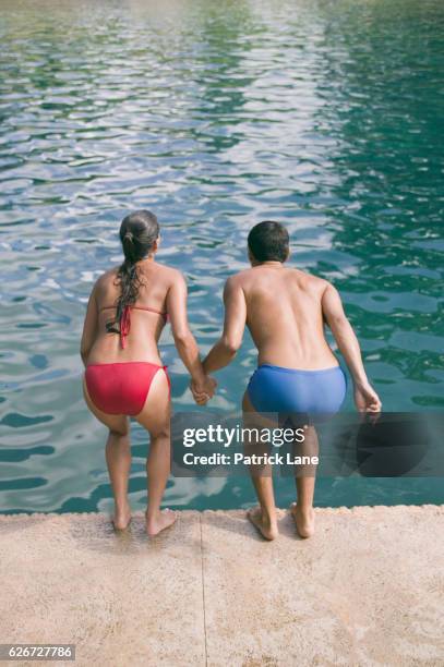 couple preparing to jump into swimming pool - jump in pool stock pictures, royalty-free photos & images