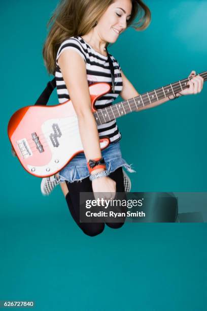 teen girl jumping and playing bass guitar - bass guitar stock pictures, royalty-free photos & images