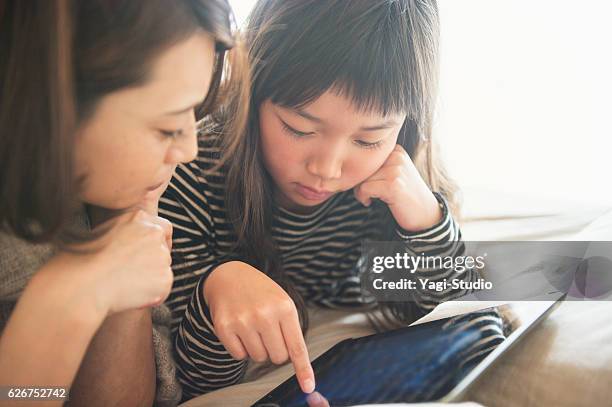 mutter und tochter spielen mit einem digitalen tablet im schlafzimmer - digital fulfillment stock-fotos und bilder