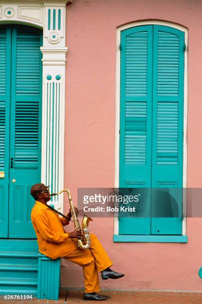 saxophonist playing outside building in the french quarter - artiste musique photos et images de collection