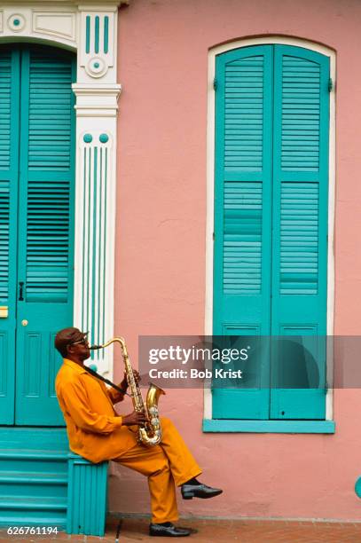 saxophonist playing outside building in the french quarter - sax stockfoto's en -beelden